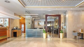 A hotel lobby with a reception desk, a seating area, and a glass partition. - Panorama by Verdi Hotels (Prague)
