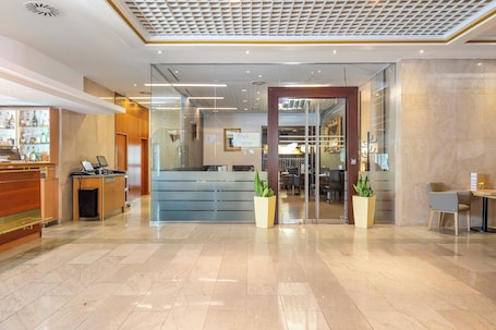 A hotel lobby with a reception desk, a seating area, and a glass partition.