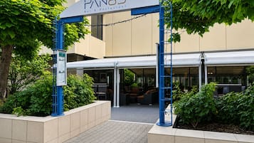 Entrada de un edificio con un letrero que dice 'PAN83 Bar & Restaurant' y un área de asientos al aire libre cubierta.