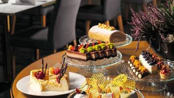 Un restaurant doté d’un bar, de tables avec des chaises et d’un présentoir où sont exposés différents desserts.