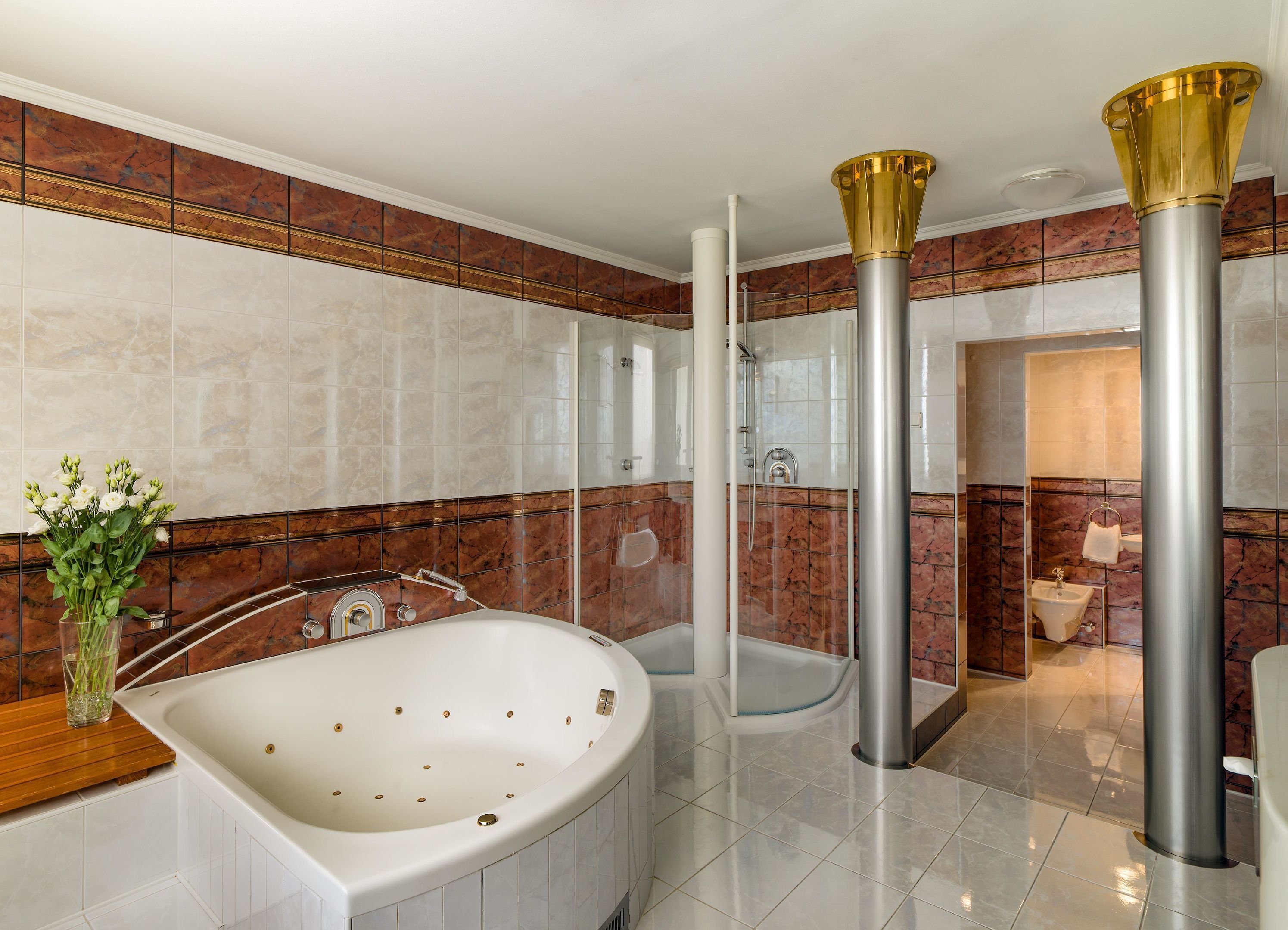 Un baño moderno con una bañera grande, ducha con cerramiento de vidrio y paredes de mármol.