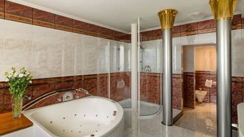 Un baño moderno con una bañera grande, ducha con cerramiento de vidrio y paredes de mármol.
