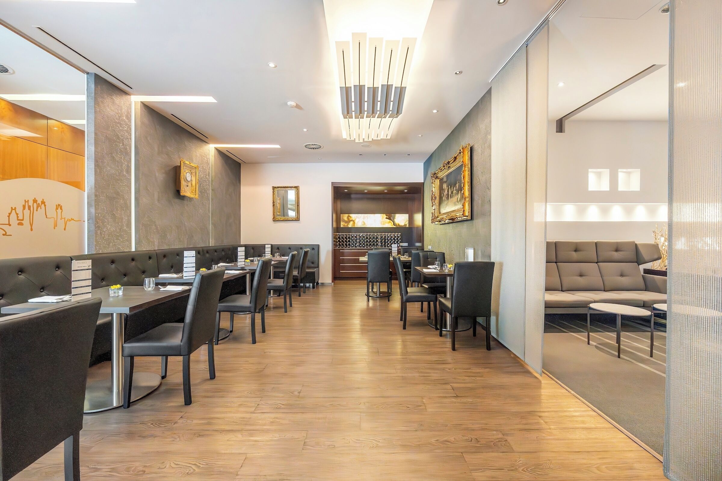 A modern restaurant with a long counter, booths, and a seating area with a sofa.