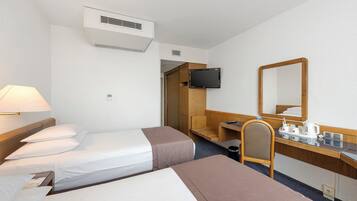A hotel room with two beds, a desk, a chair, a television, and a mirror.