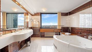 A modern bathroom with dual sinks, a large bathtub, and a view of a cityscape.