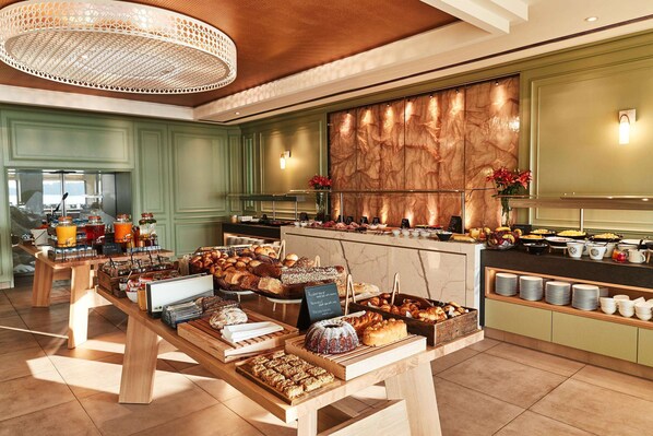 A buffet area with various food items and a marble wall in the background.