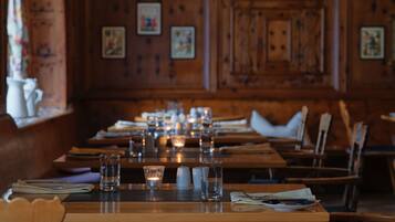 A restaurant with wooden interiors, long tables set with glasses, candles, and cutlery.