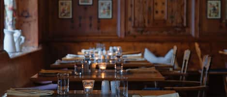 Un restaurante con interiores de madera, largas mesas dispuestas con copas, velas y cubiertos.