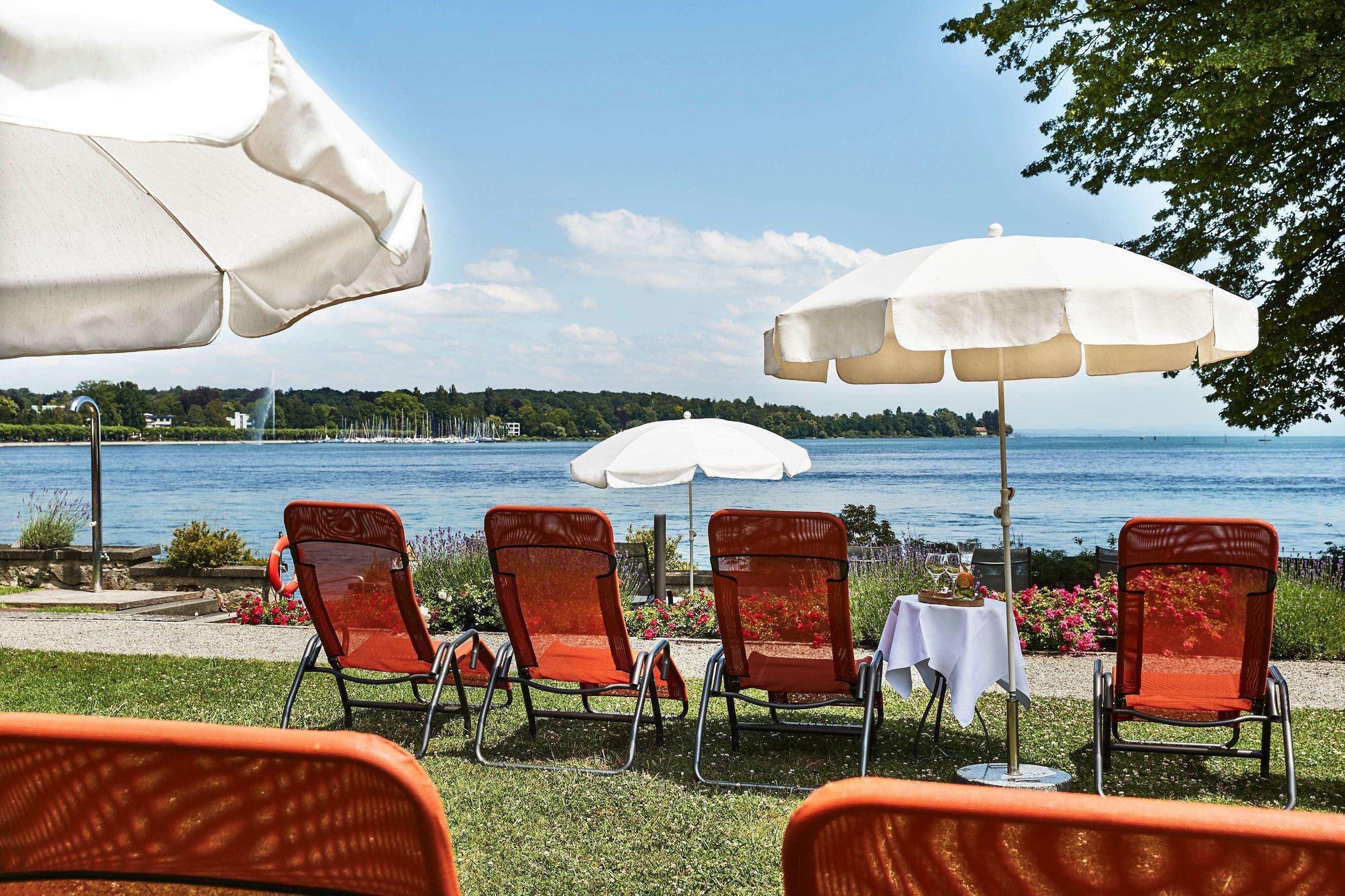 Outdoor seating with umbrellas, a table, and a view of a lake.