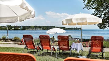 Outdoor seating with umbrellas, a table, and a view of a lake.