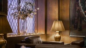 A cozy living room with a leather sofa, a table with a lamp, and a decorative vase with branches.
