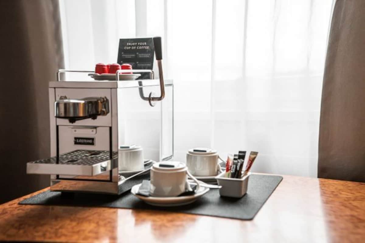 Máquina de café com xícaras e um aviso sobre uma mesa.