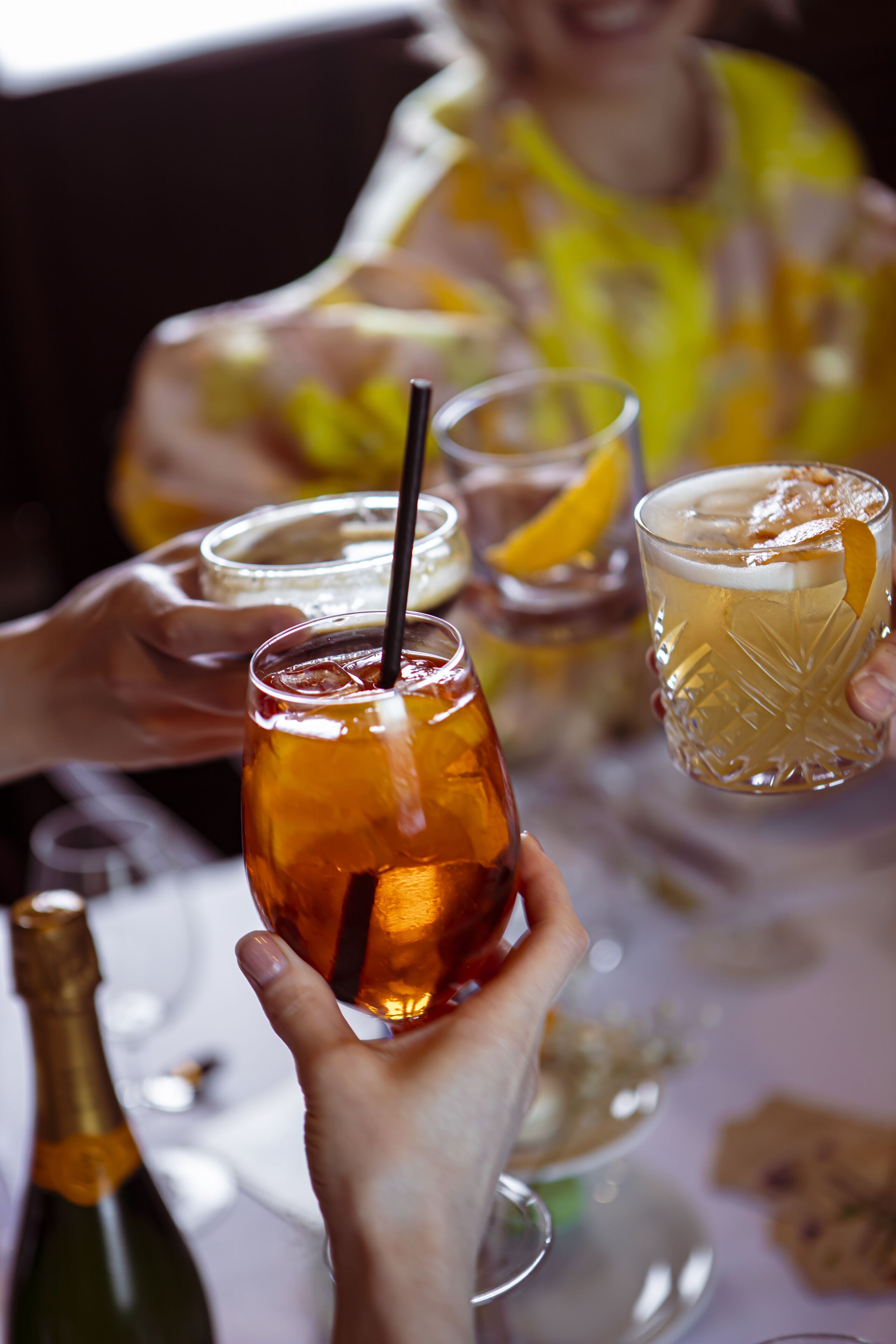 En grupp människor som håller i glas med dryck, en flaska och ett glas på ett bord.
