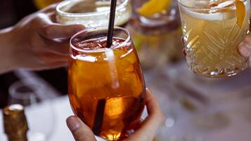 En grupp människor som håller i glas med dryck, en flaska och ett glas på ett bord.
