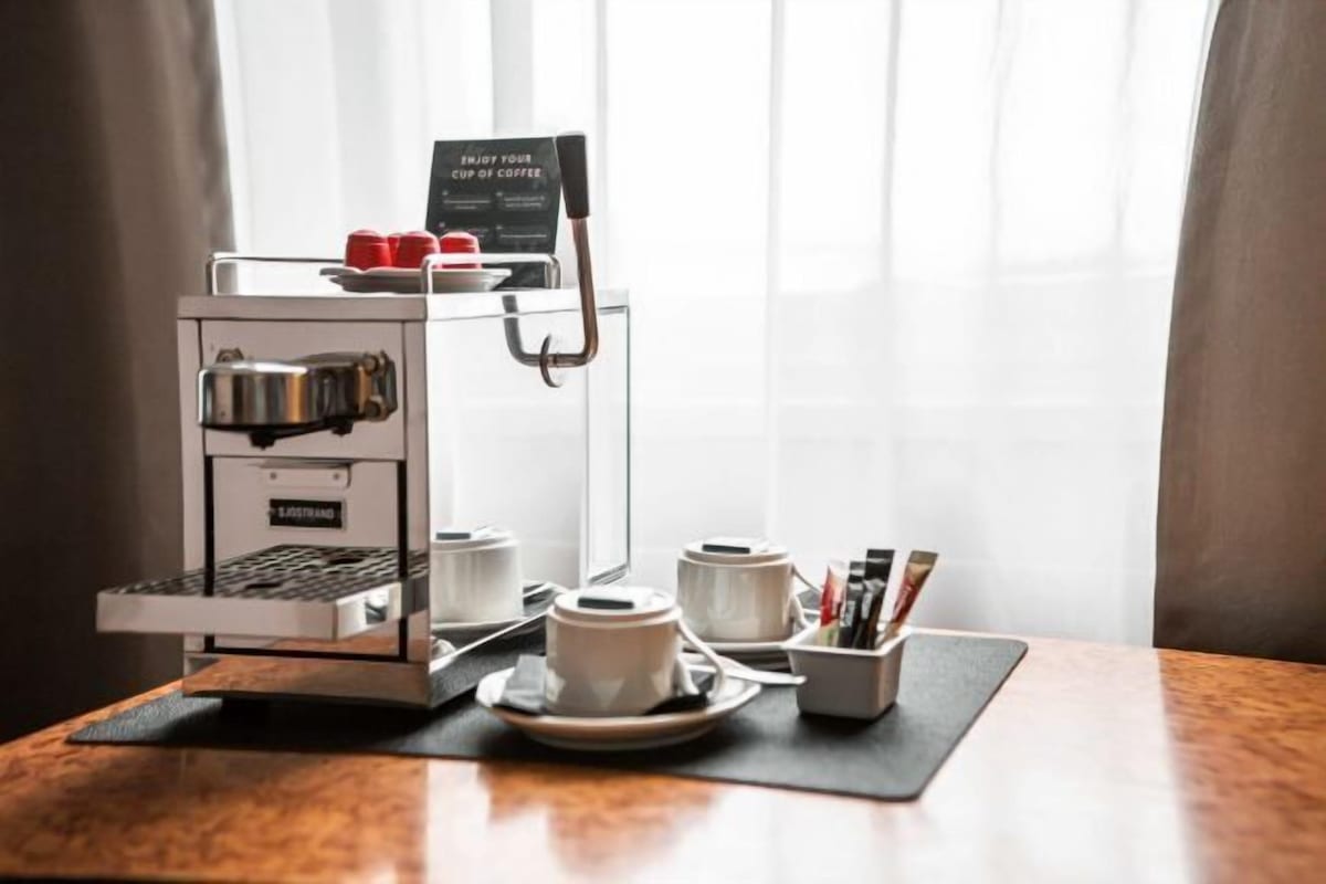 Een koffieapparaat met kopjes en een bordje op een tafel.