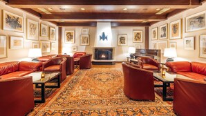 A spacious lobby with leather sofas, a large patterned rug, and framed artwork on the walls.