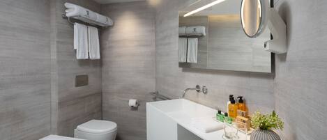 Un baño moderno con bañera, inodoro y tocador con espejo.