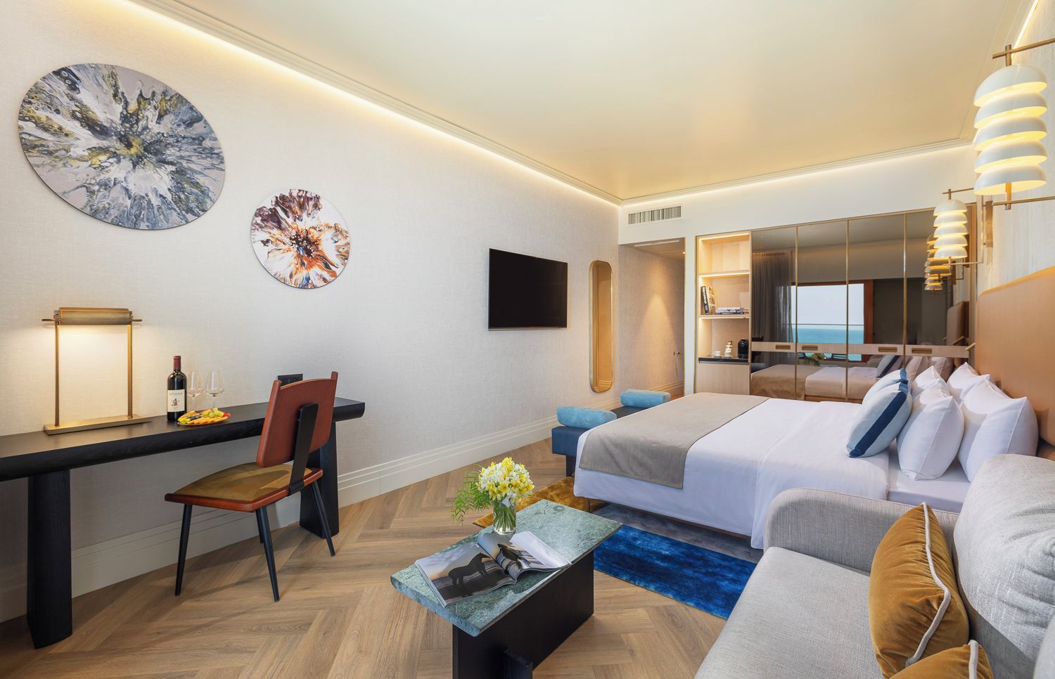 Quarto de hotel moderno com cama, área de estar, escrivaninha e televisão.