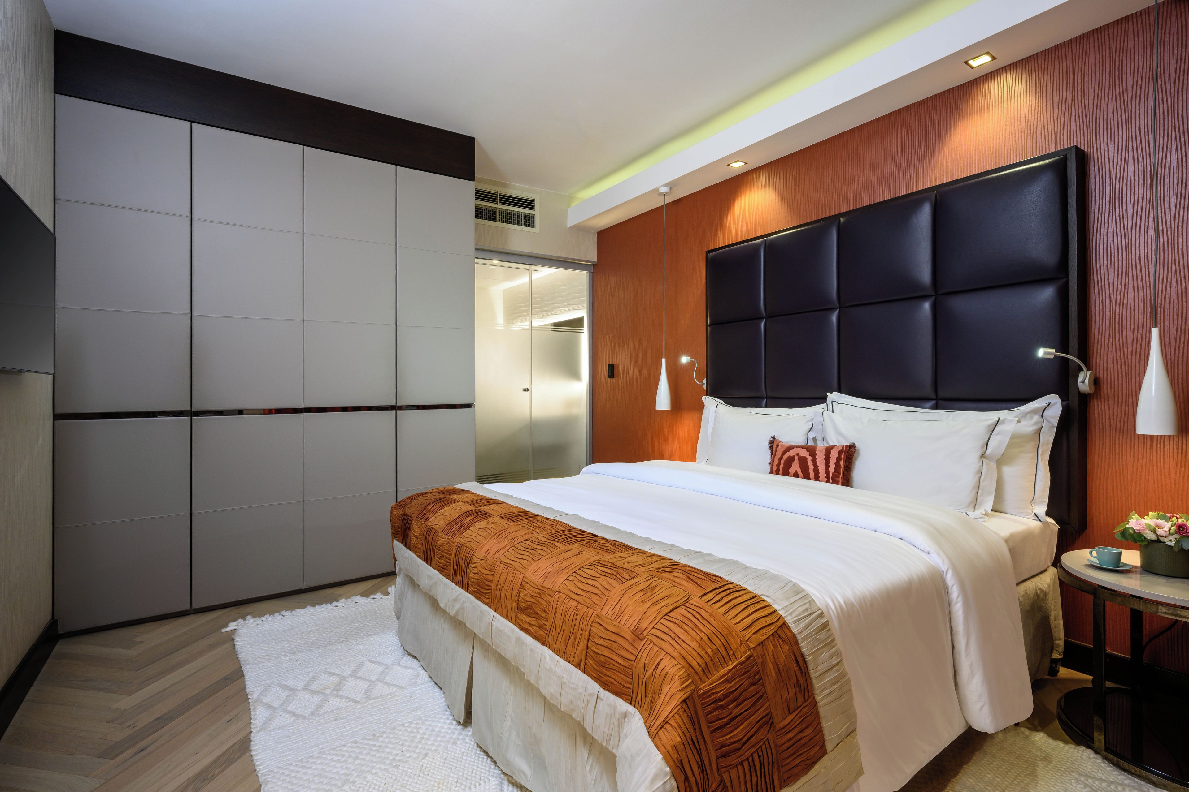 Een moderne slaapkamer met een groot bed, een garderobe en een nachtkastje met een lamp.