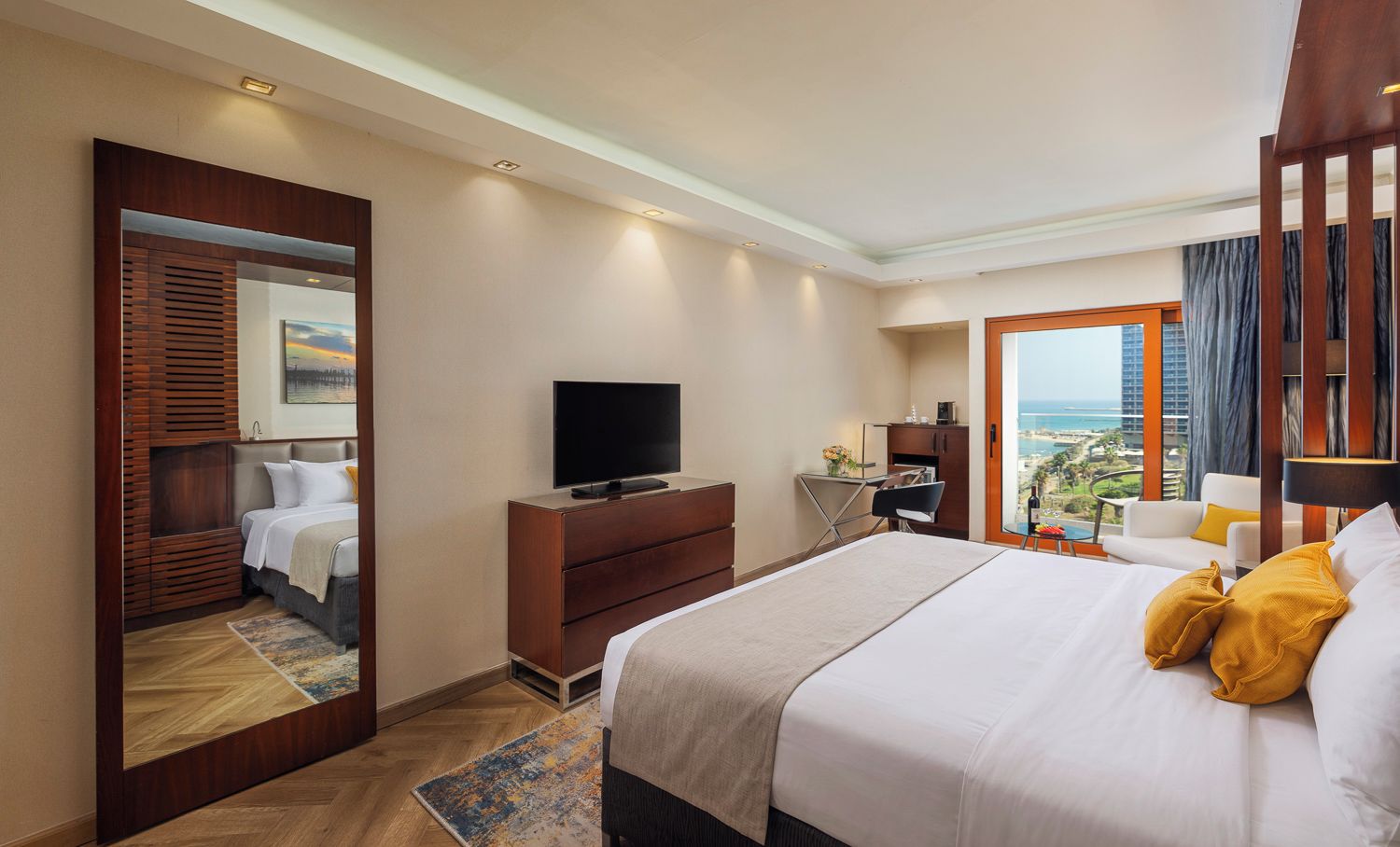 Une chambre d’hôtel avec un lit, une télévision, un bureau et une vue sur l’océan.