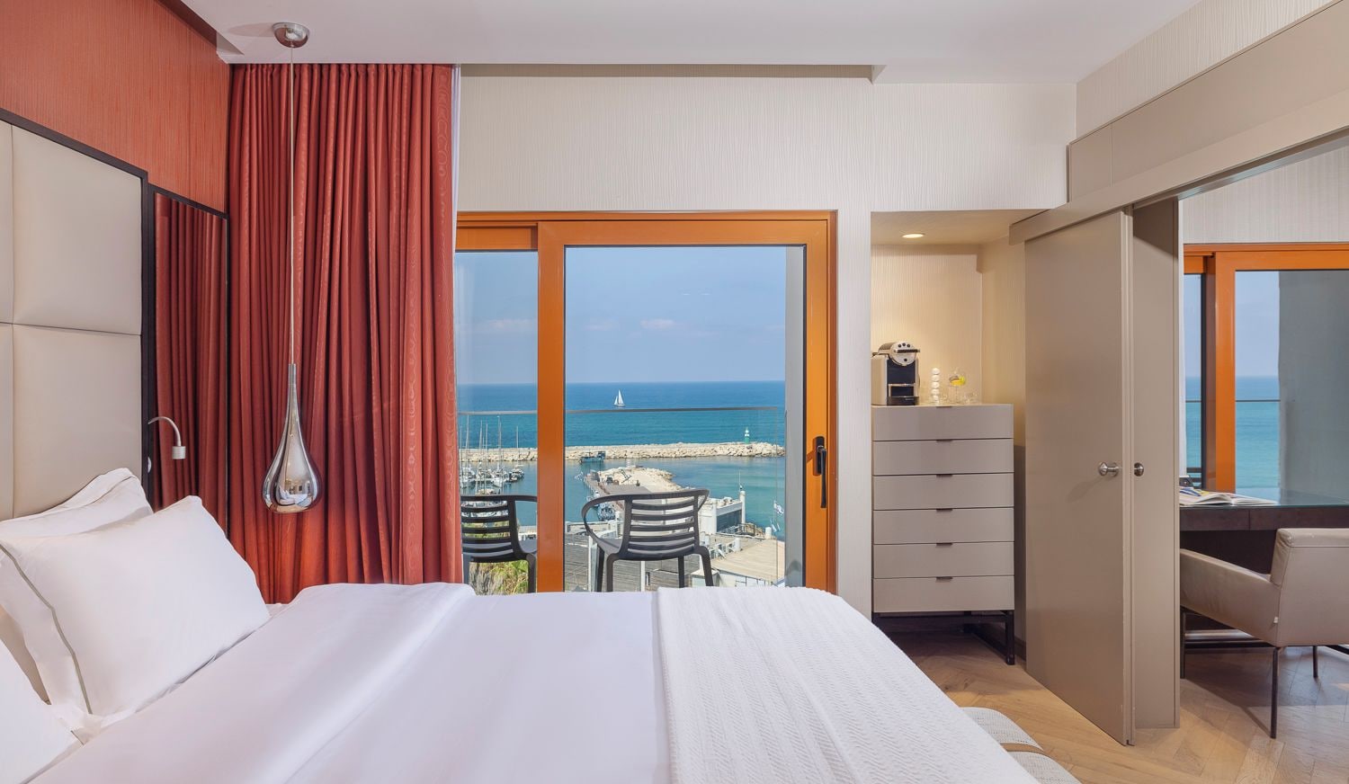 Habitación de hotel con cama, escritorio, silla y vista al mar.