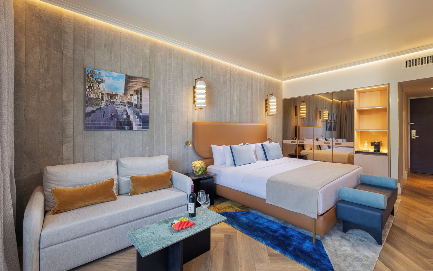 Una habitación de hotel moderna con una cama grande, un sofá, una mesa de centro y una pequeña zona de estar.