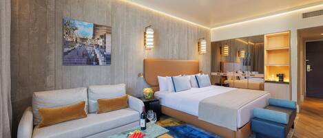 Una habitación de hotel moderna con una cama grande, un sofá, una mesa de centro y una pequeña zona de estar.
