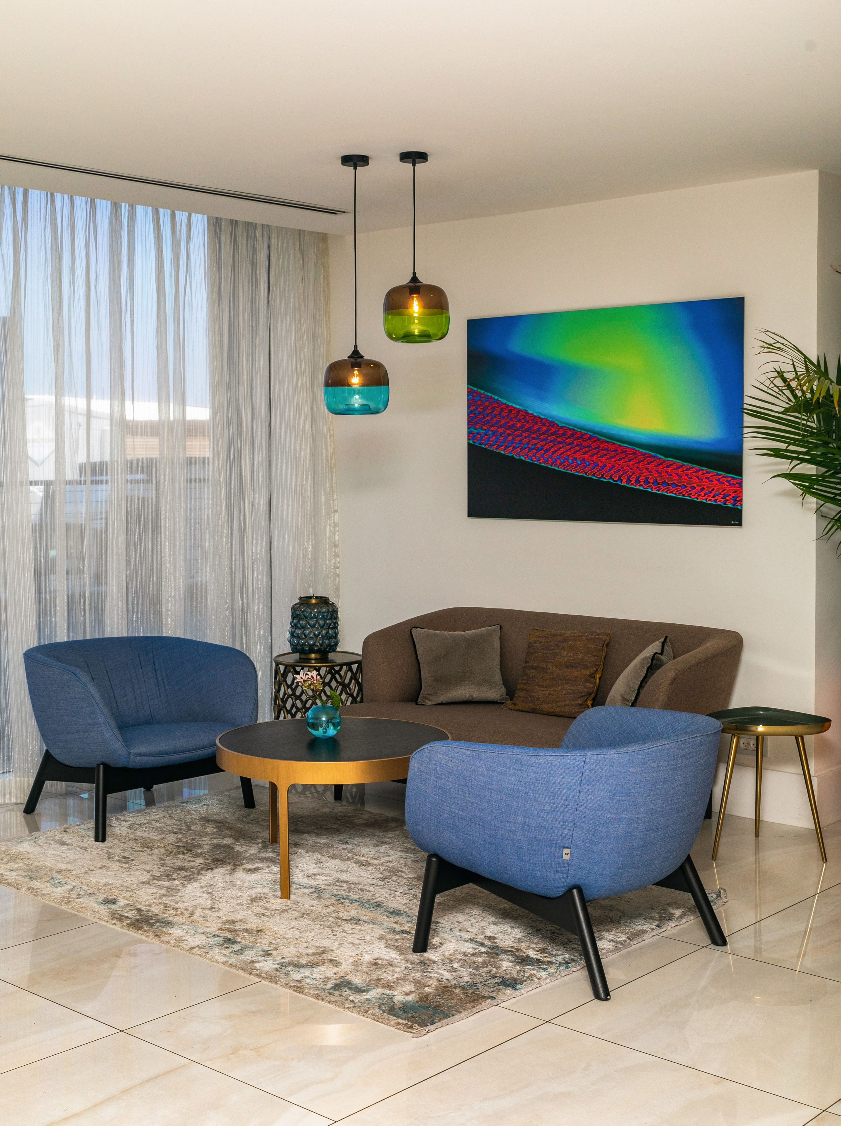 A modern living room with a sofa, two armchairs, a coffee table, and a painting on the wall.