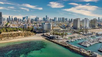 A coastal cityscape with a marina, high-rise buildings, and a clear sky.