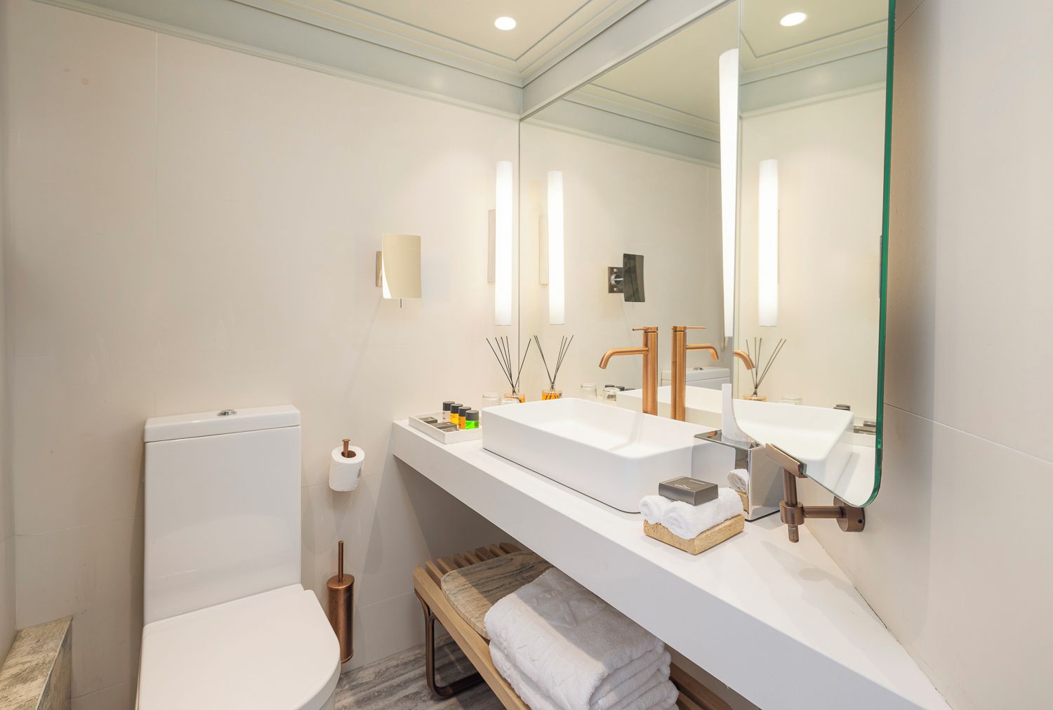 A modern bathroom with a toilet, a large sink, a mirror, and a towel rack.