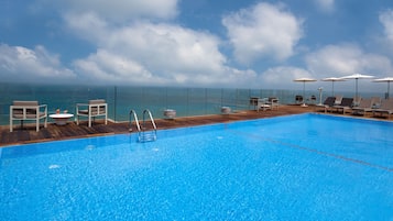 Alberca al aire libre, sombrillas en la alberca y camastros