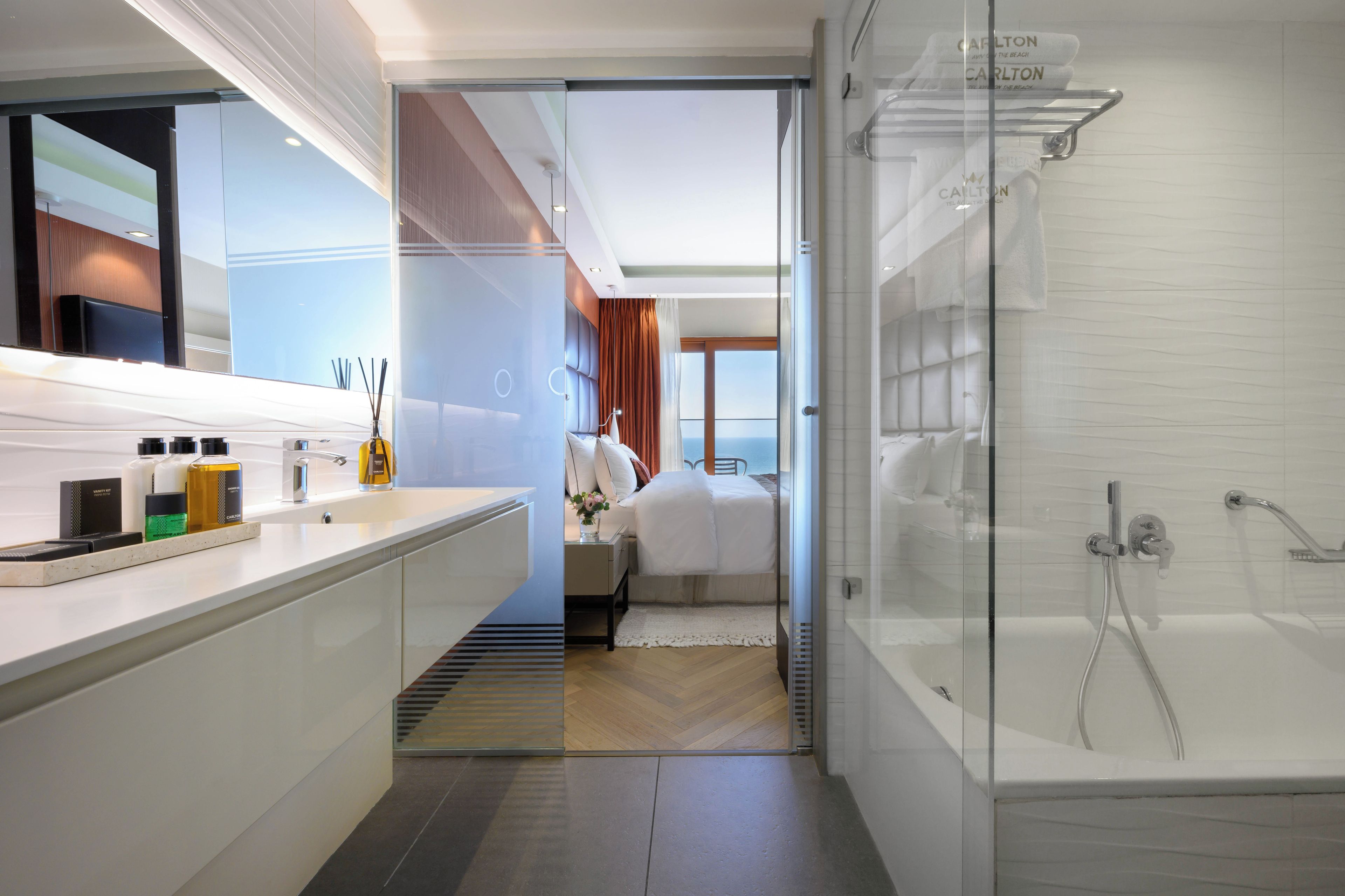Un baño moderno con cabina de ducha de vidrio, tocador con artículos de aseo y vistas al exterior.