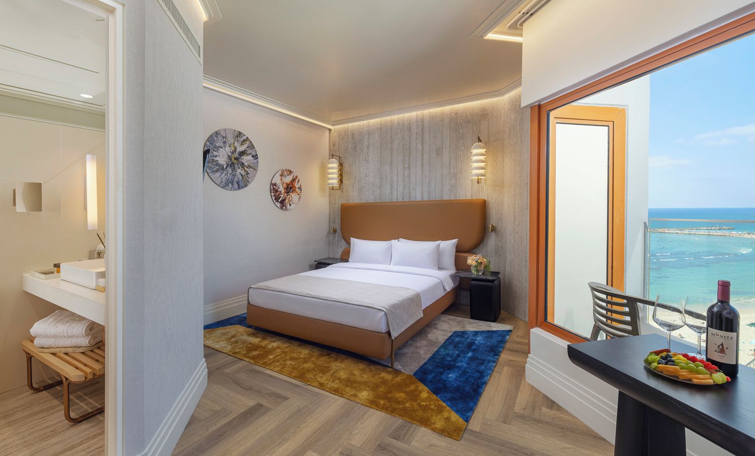 A hotel room with a bed, bedside table, and a view of the sea.