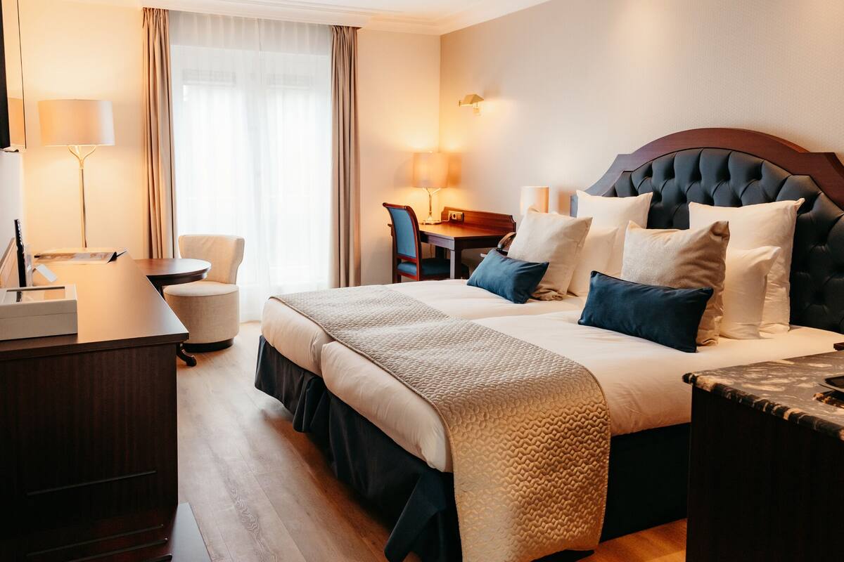 A hotel room with a large bed, bedside tables, a desk, and a chair.