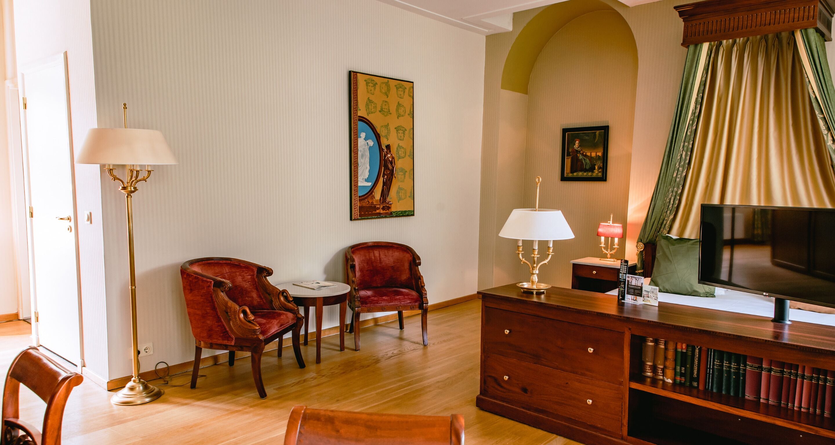 Una habitación con dos sillones de cuero rojo, un mueble de madera con libros, un televisor y una lámpara de pie.