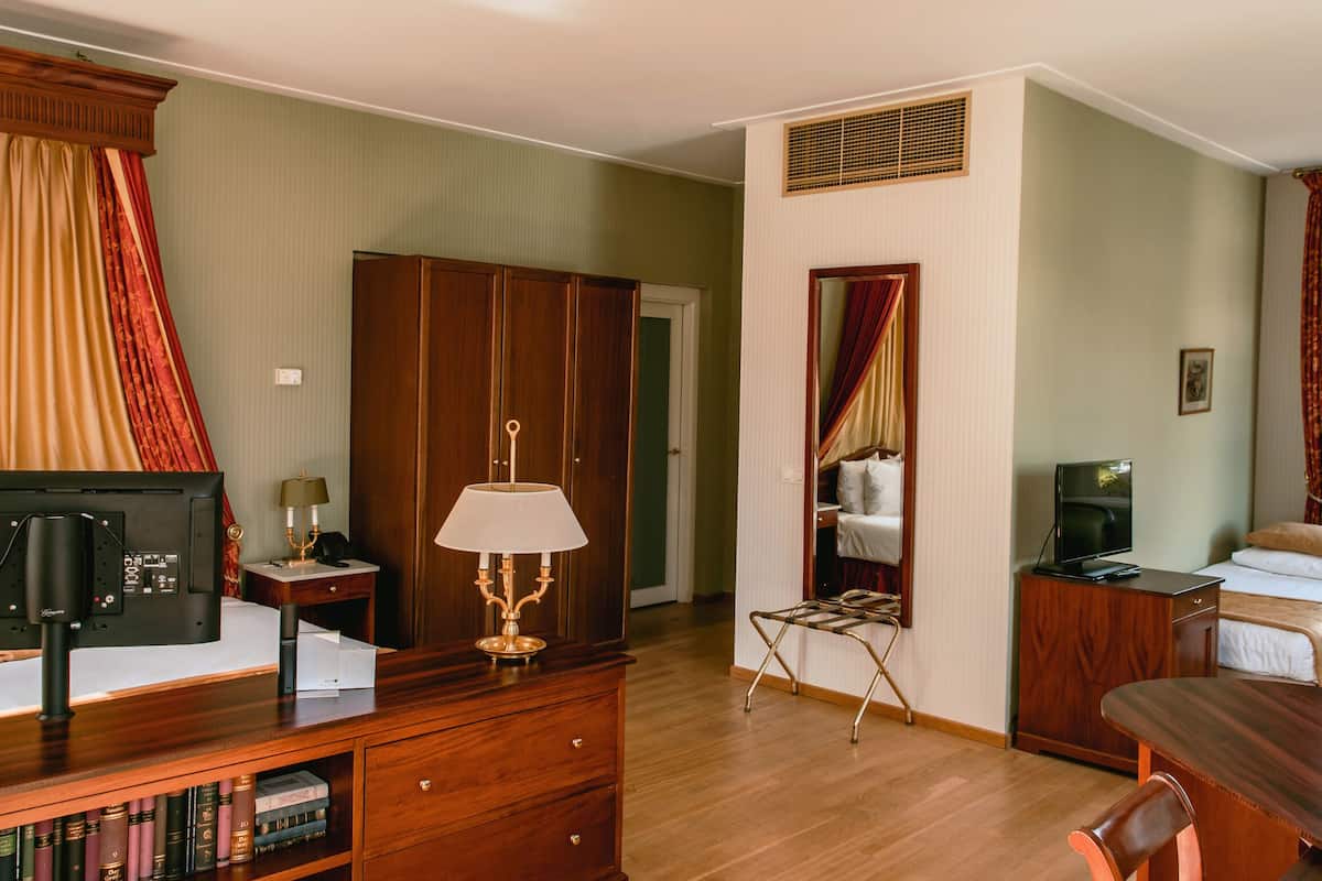 A hotel room with a bed, a desk, a television, a bookshelf, a wardrobe, and a bathroom.
