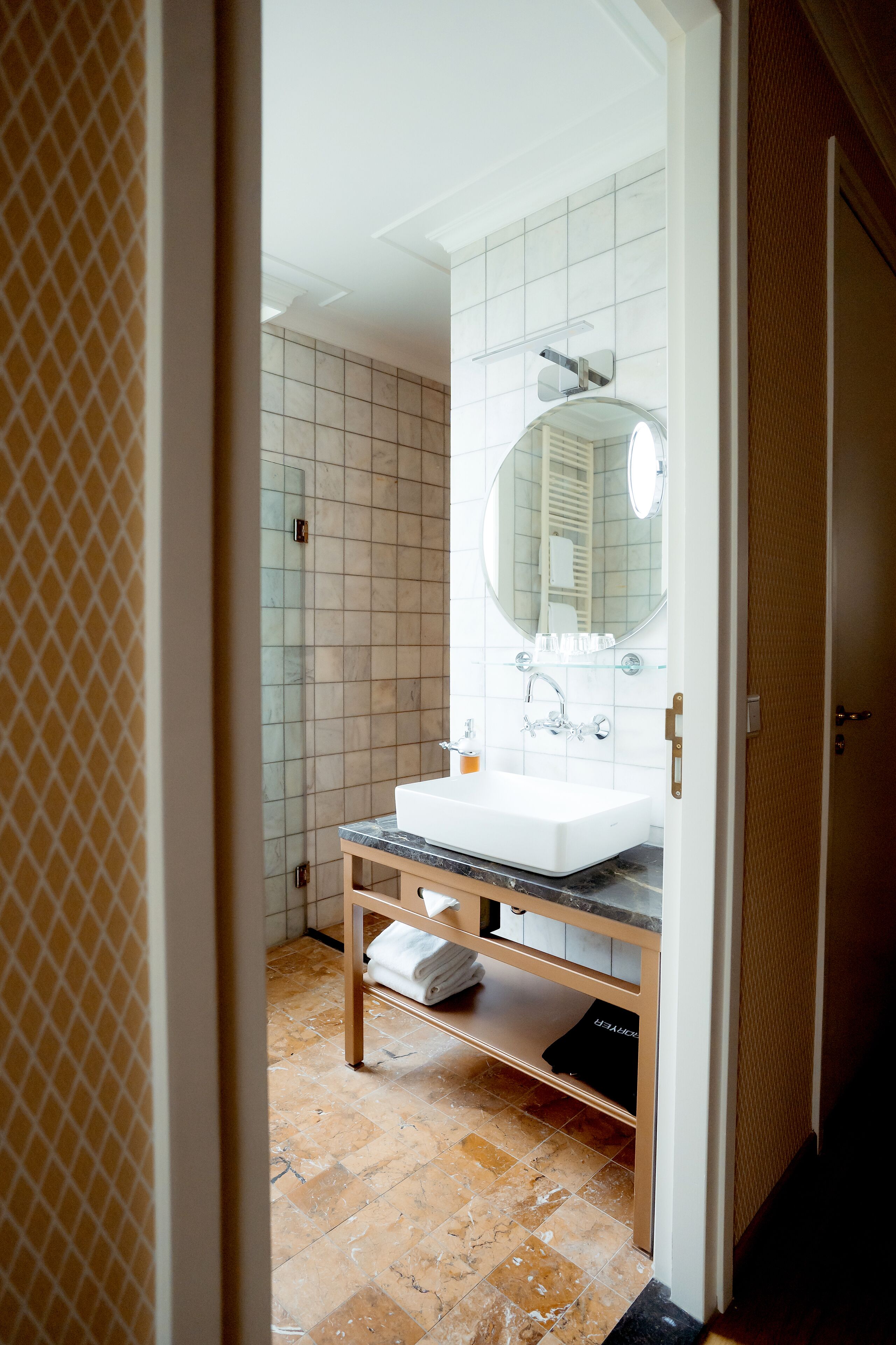 A bathroom with a white sink, a mirror, and a tiled wall.