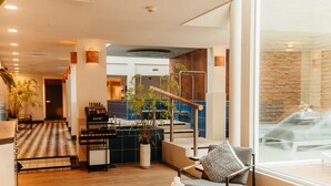 Un moderno vestíbulo de hotel con mostrador de recepción, zona de estar y una escalera que conduce a los pisos superiores.