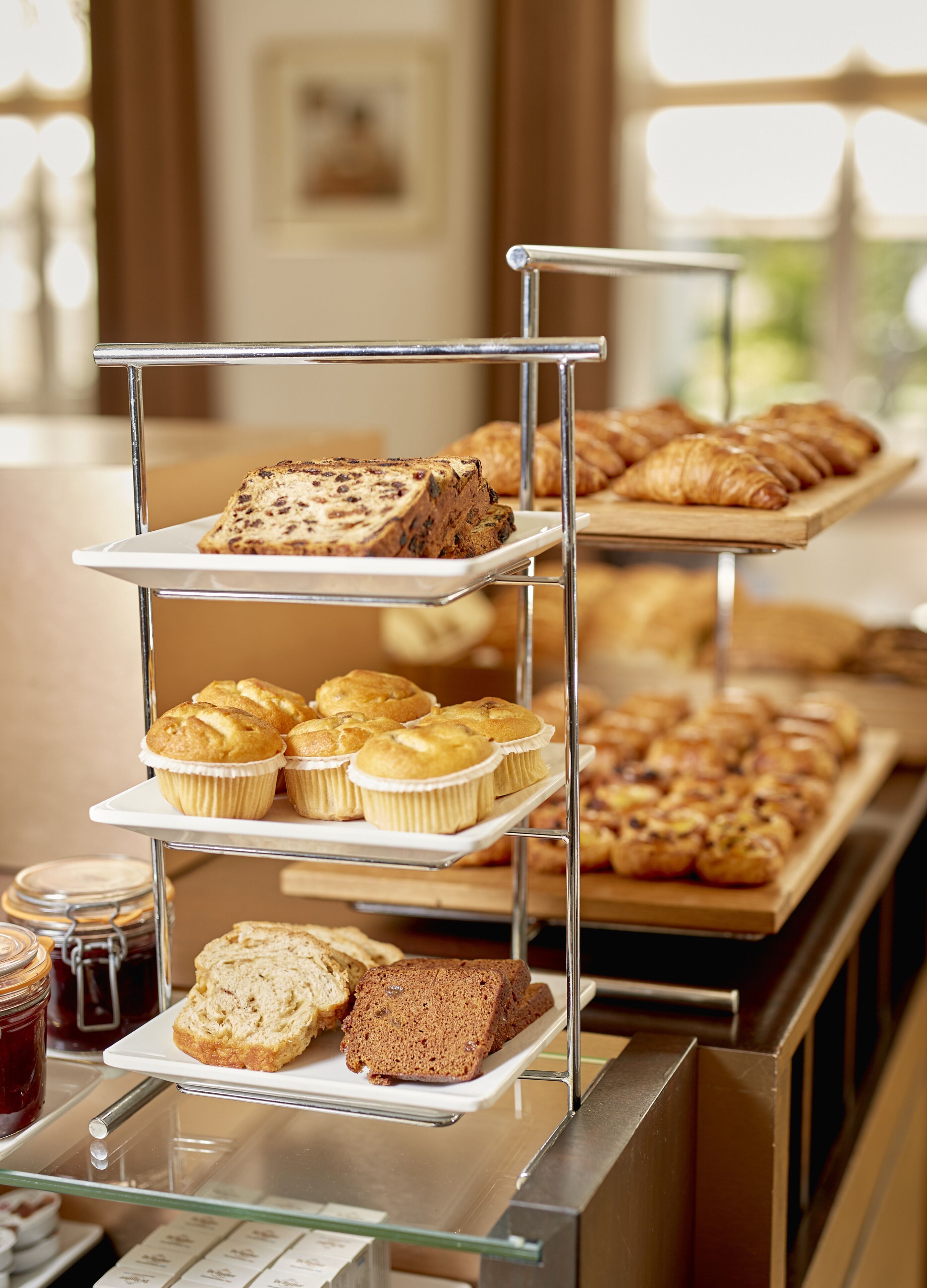 Een meerlaagse presentatie van gebakjes en muffins in een bakkerij.