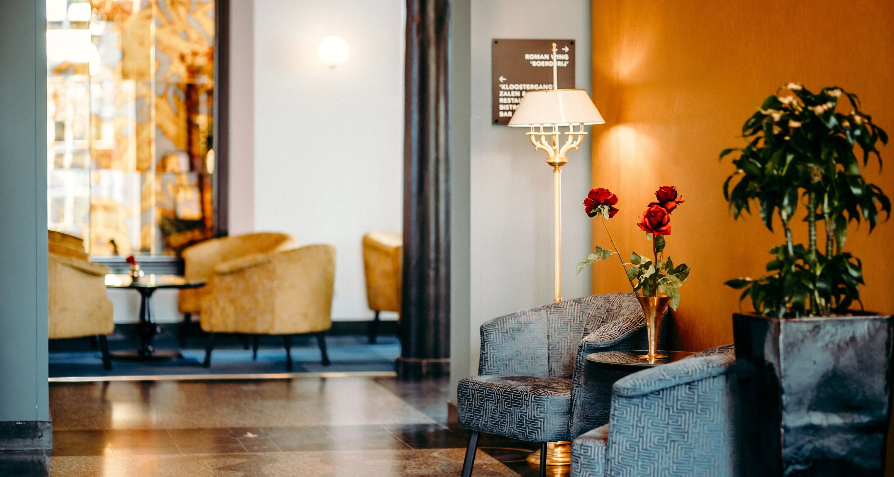 A hotel lobby with seating, a lamp, and a sign indicating directions to the restaurant and bar.