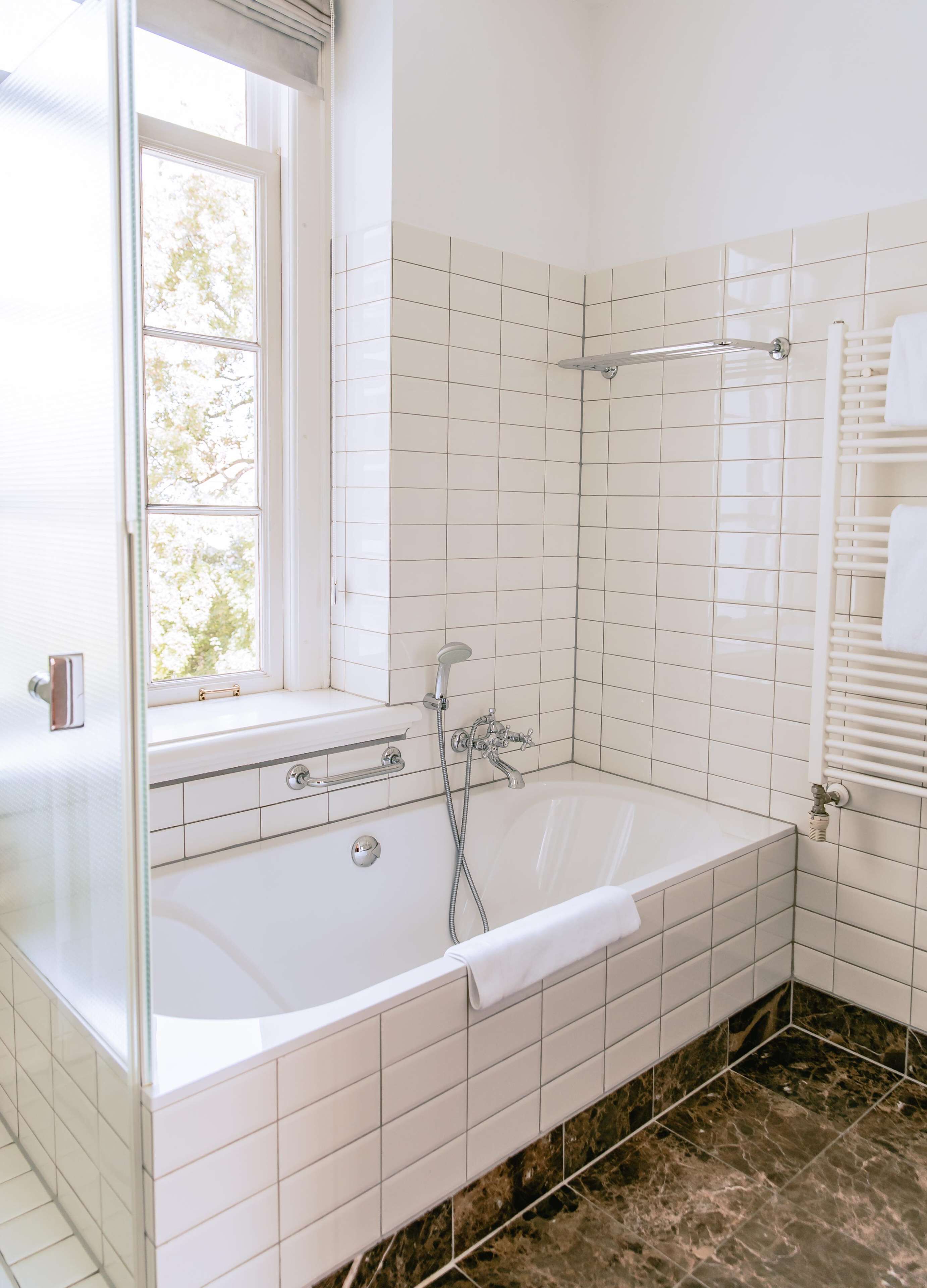 A modern bathroom with a large bathtub, a window, and a shower area.