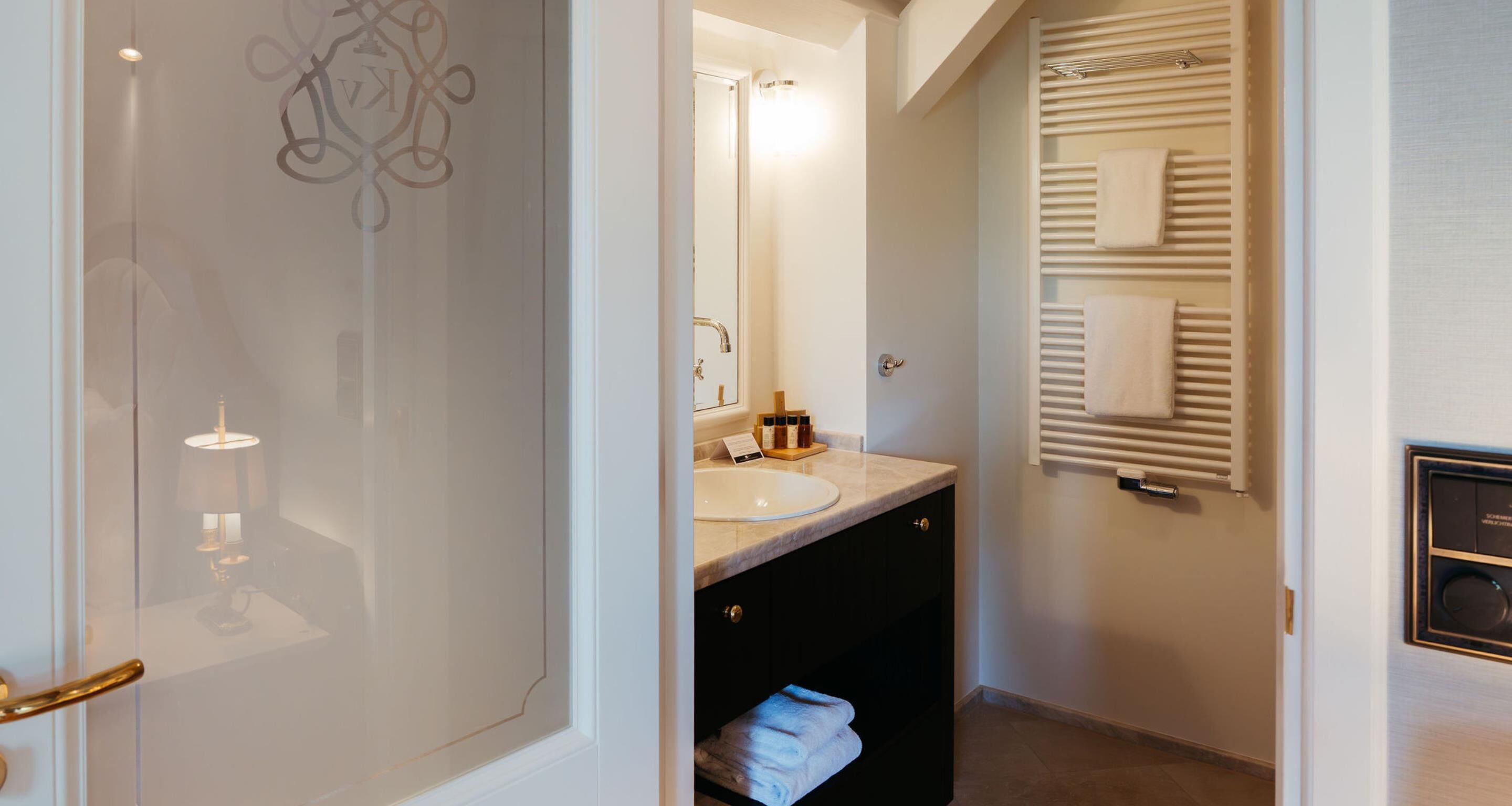 A modern bathroom with a vanity, a towel rack, and a heated towel rail.