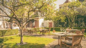 An outdoor dining area with tables and chairs, surrounded by trees and a hedge. - Grand Hotel Karel V, WorldHotels Luxury (Utrecht)