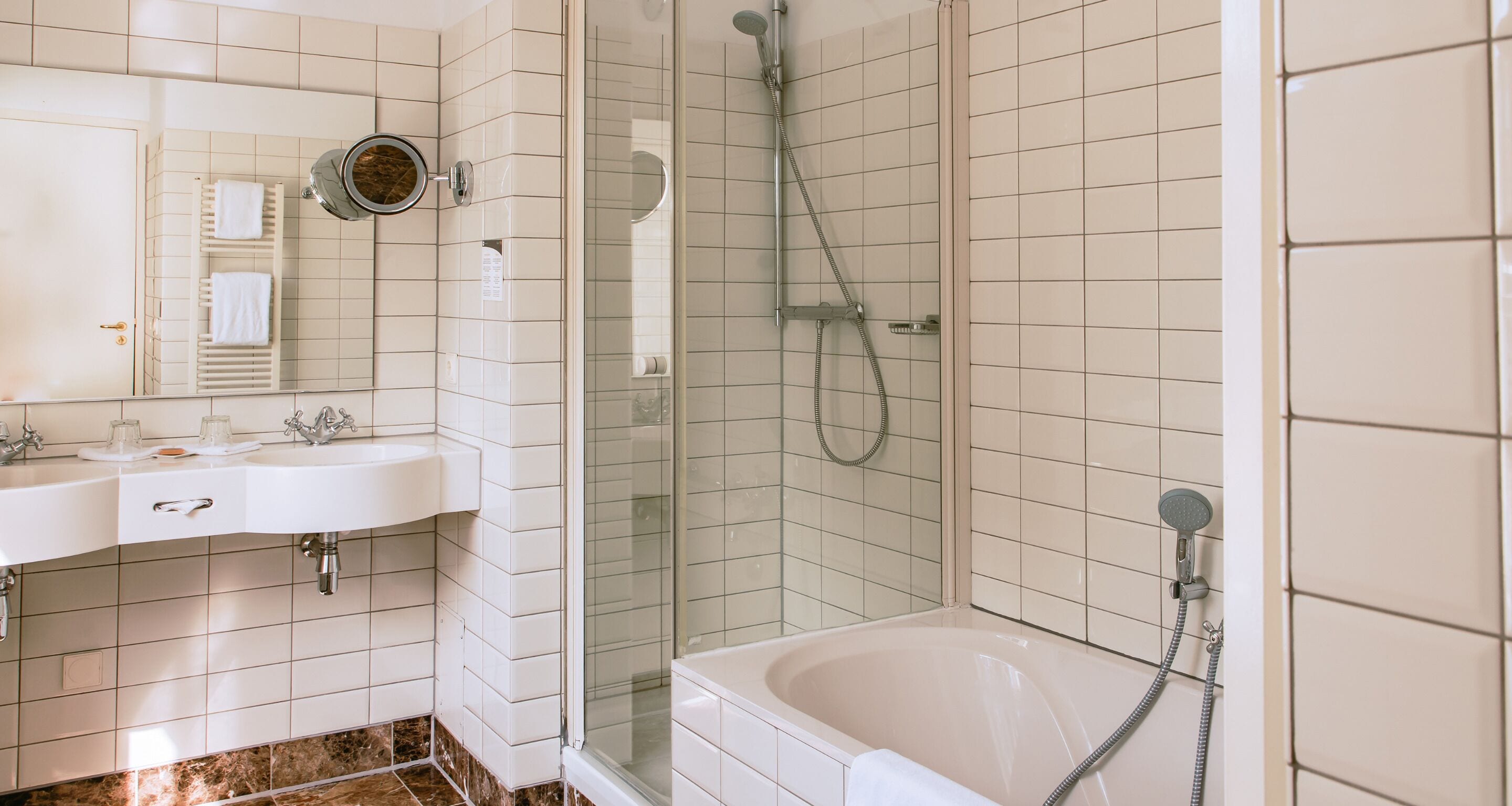 A modern bathroom with a glass-enclosed shower, a white sink with a mirror, and a bathtub.
