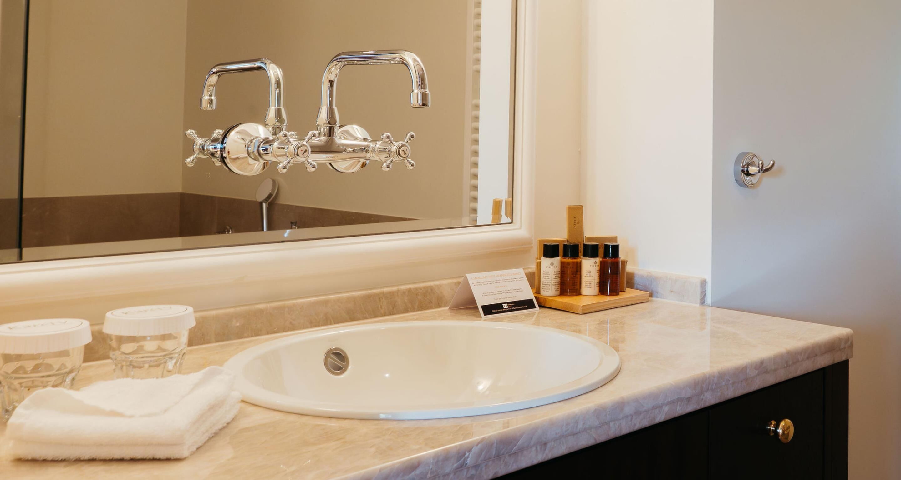 A bathroom with a white sink, a mirror, a towel, and toiletries on the counter.