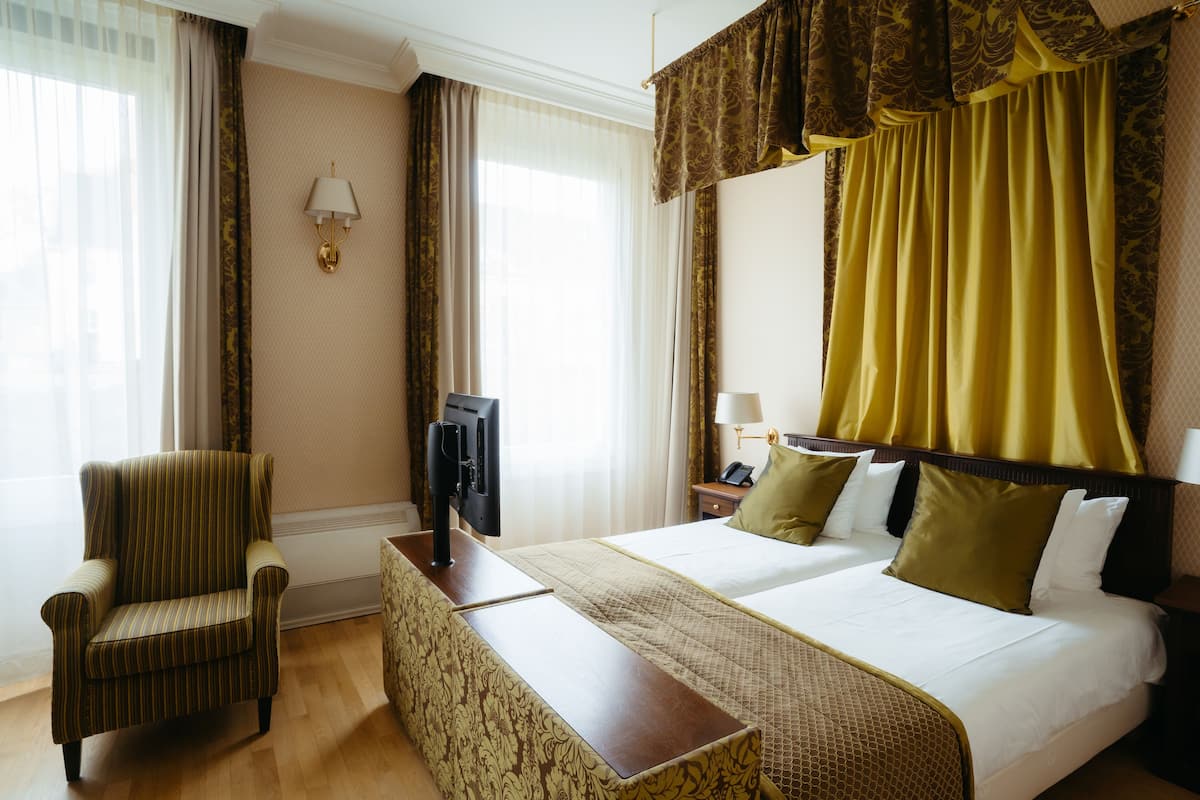 A hotel room with a bed, a TV, a chair, and a desk.