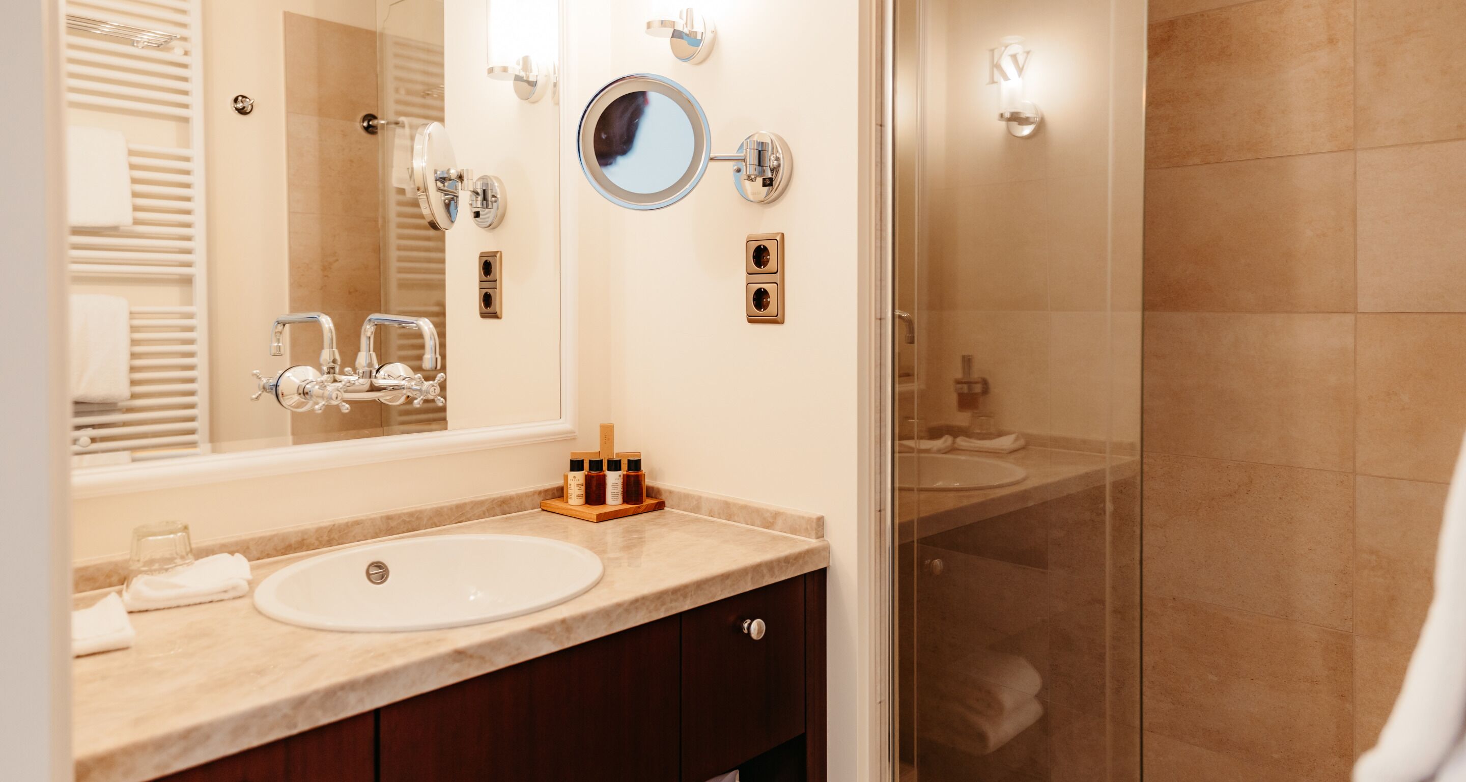 A modern bathroom with a large mirror, a sink, and a glass shower enclosure.