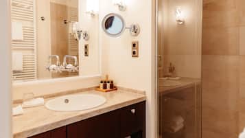 A modern bathroom with a large mirror, a sink, and a glass shower enclosure.