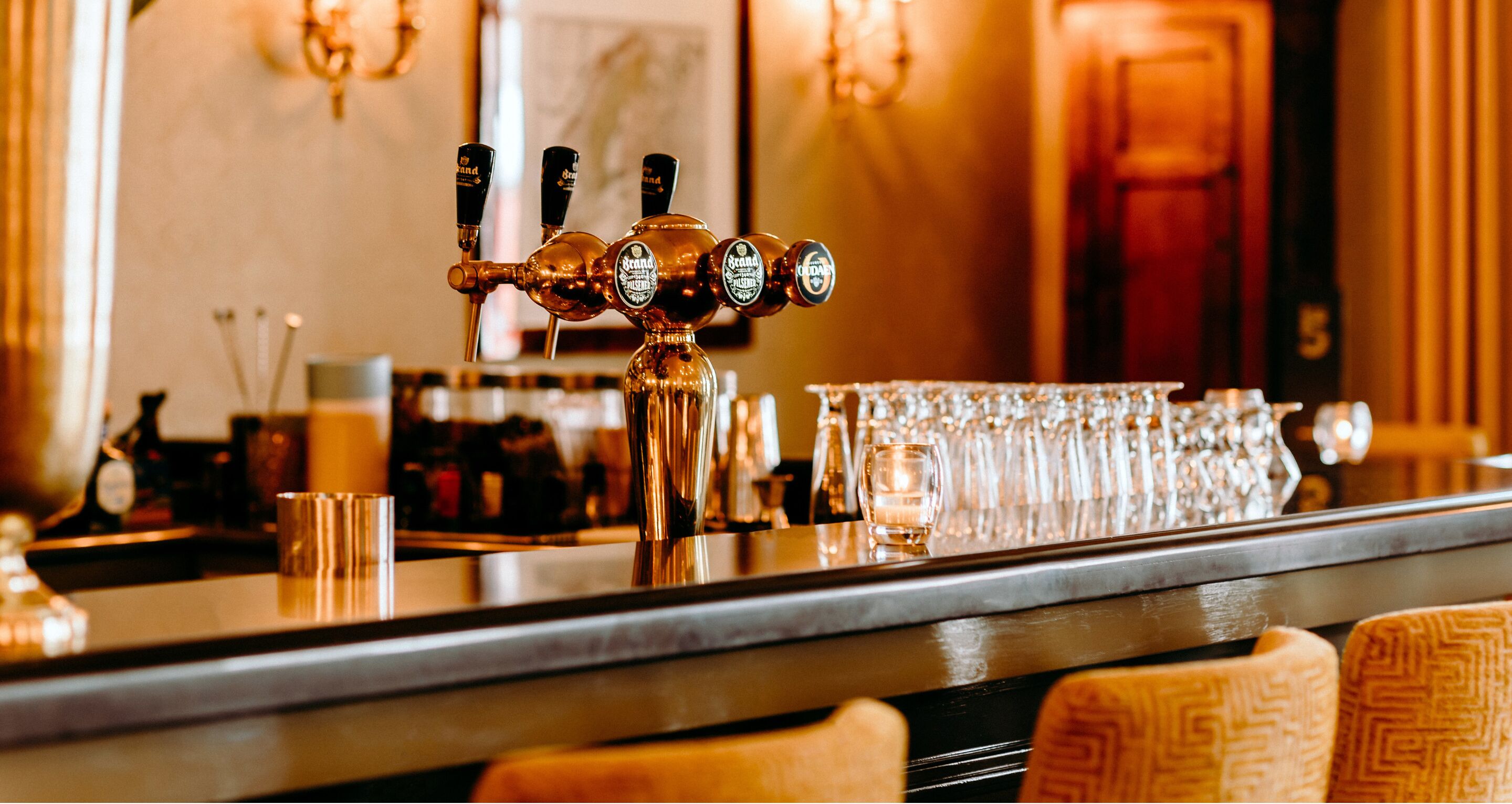 A bar area with a tap, glasses, and a candle.