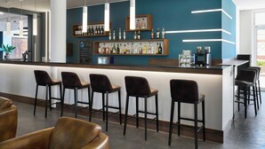 Zona de bar moderna con una pared azul de acento, taburetes y una variedad de botellas de licor.